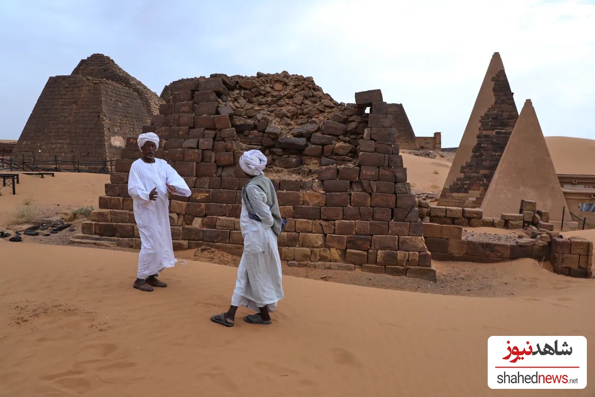 A guide, left, speaks with a visitor at the Meroe archaeological site.
